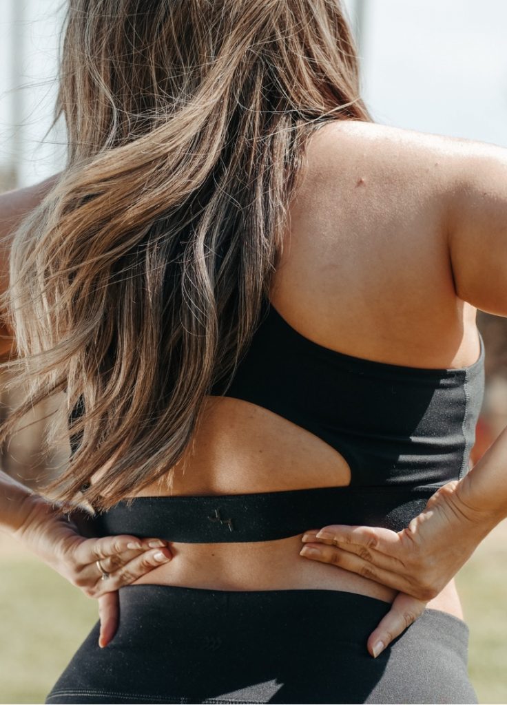 Woman feeling her lower back as she experiences pain