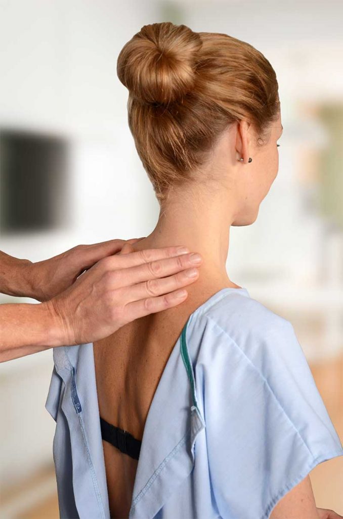 Chiropractor assessing woman's lower neck